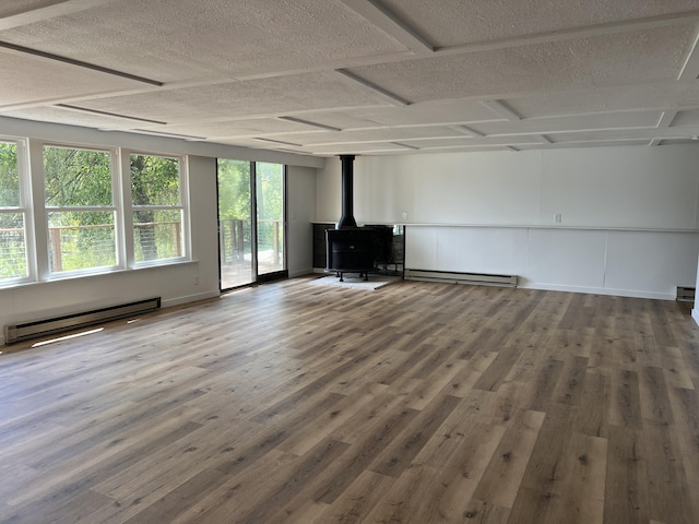 unfurnished living room with a wood stove, wood finished floors, and a baseboard radiator