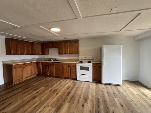 kitchen with white appliances, light countertops, light wood-type flooring, and a sink