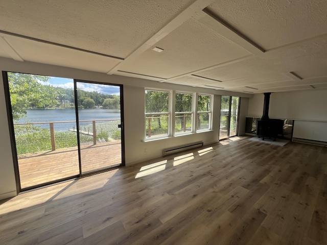 unfurnished sunroom with a baseboard heating unit, a wood stove, and a water view