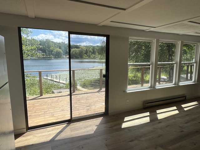 unfurnished sunroom featuring a baseboard radiator, a water view, and a healthy amount of sunlight