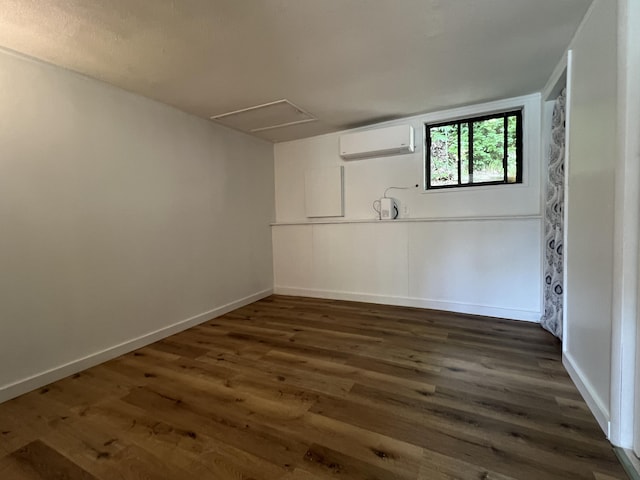 basement with baseboards, wood finished floors, and a wall unit AC