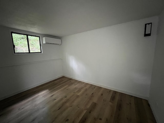 empty room featuring baseboards, wood finished floors, and a wall unit AC