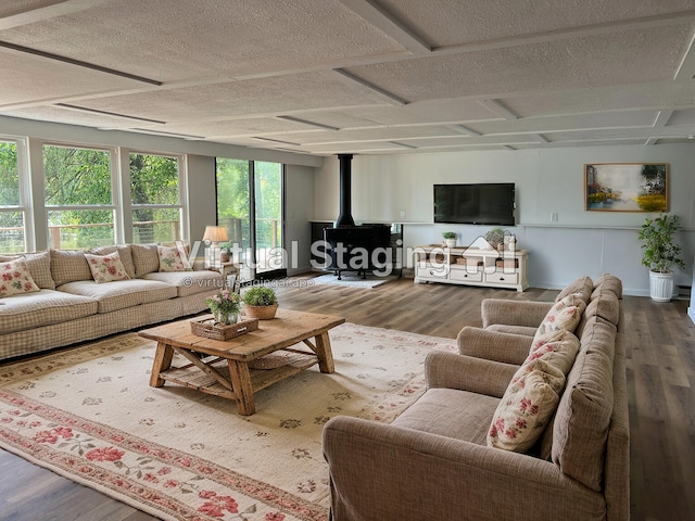 living area featuring a wood stove, wood finished floors, baseboards, and a textured ceiling