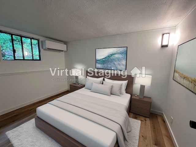 bedroom with a textured ceiling, a wall mounted AC, baseboards, and wood finished floors