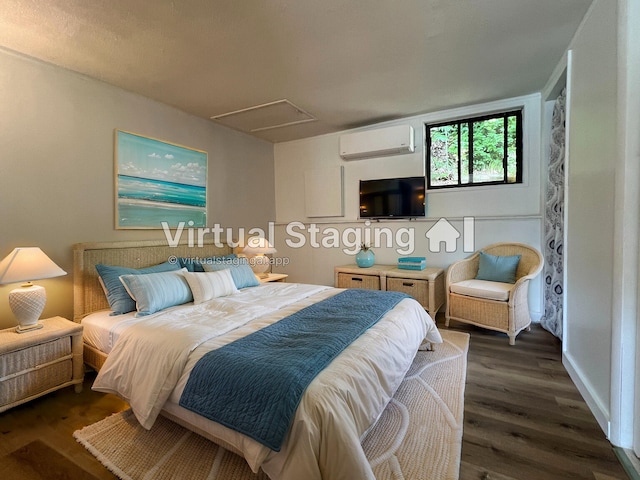 bedroom with an AC wall unit, attic access, wood finished floors, and baseboards