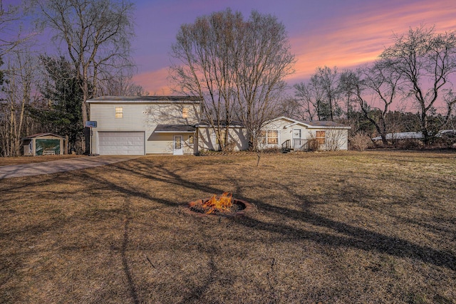 view of front facade featuring a garage, a fire pit, a front yard, and driveway