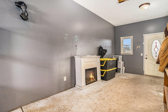 carpeted living room featuring a glass covered fireplace and a textured ceiling