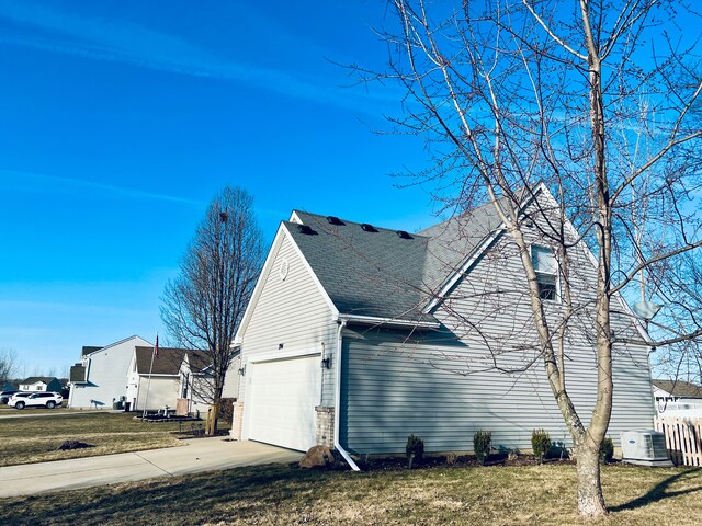 view of home's exterior with a yard, concrete driveway, an attached garage, a shingled roof, and brick siding