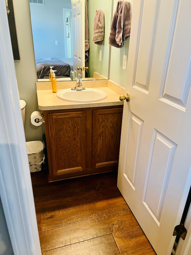 ensuite bathroom with vanity, wood finished floors, visible vents, and ensuite bathroom