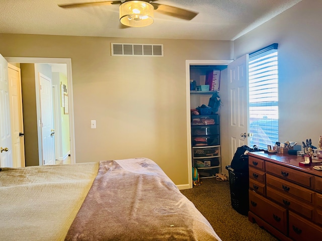 bedroom featuring a textured ceiling, visible vents, dark colored carpet, and ceiling fan