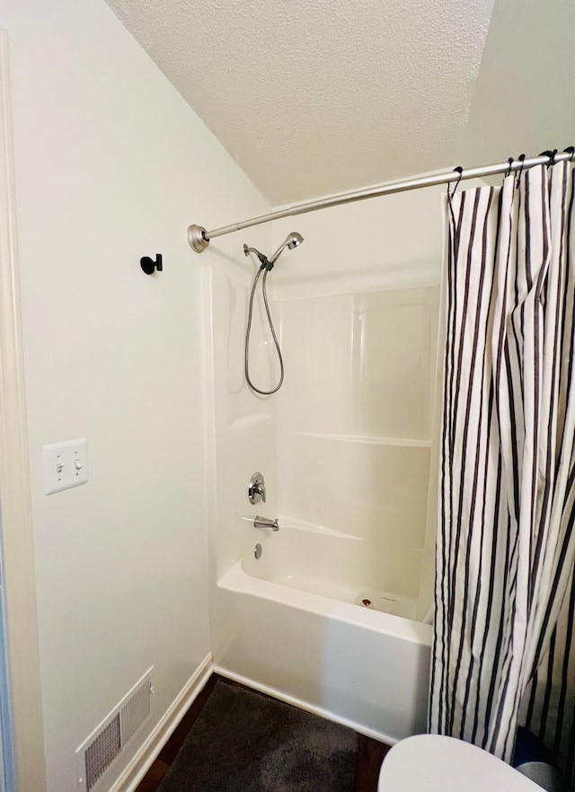 full bathroom featuring visible vents, toilet, a textured ceiling, and shower / tub combo