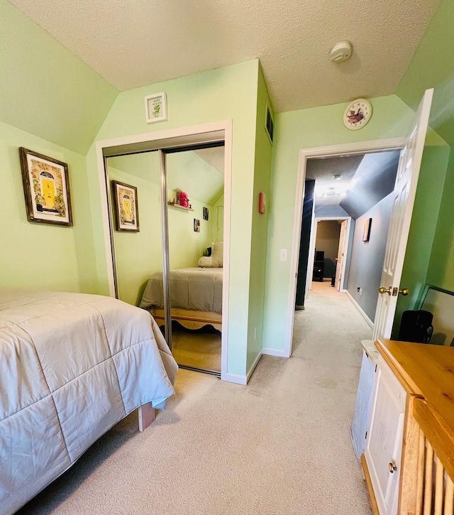 bedroom with baseboards, vaulted ceiling, light carpet, a closet, and a textured ceiling