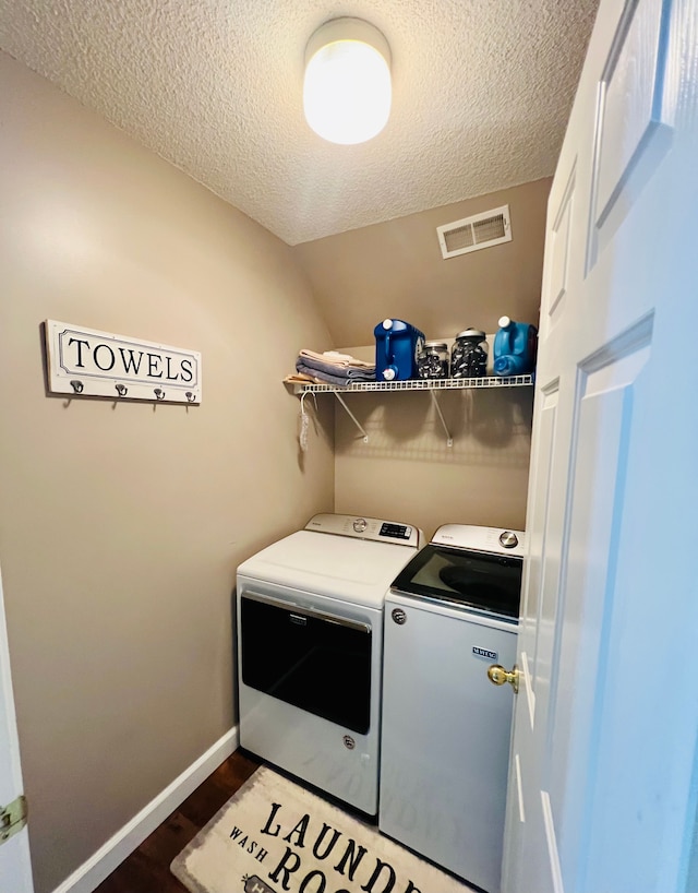 laundry room featuring visible vents, dark wood-type flooring, washer and dryer, a textured ceiling, and laundry area