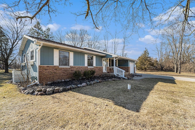 ranch-style home featuring a front yard, a garage, brick siding, and driveway