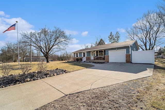 ranch-style home featuring fence, concrete driveway, a front yard, an attached garage, and brick siding