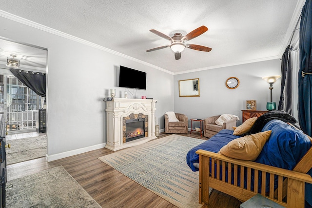 living area with wood finished floors, a lit fireplace, ornamental molding, and a textured ceiling