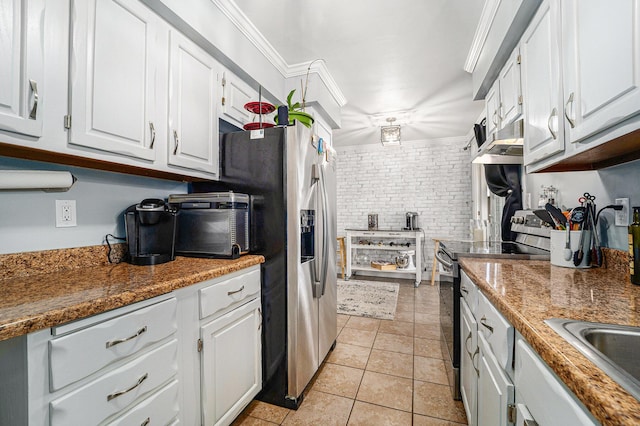 kitchen with light tile patterned floors, brick wall, electric range, ornamental molding, and white cabinetry