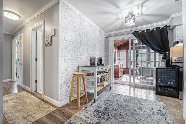 foyer entrance featuring brick wall, wood finished floors, baseboards, and ornamental molding