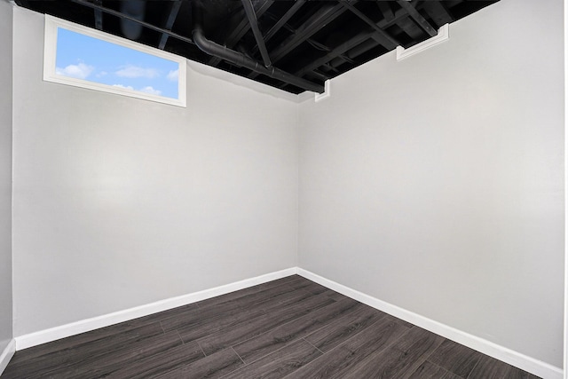 spare room featuring dark wood-style floors and baseboards