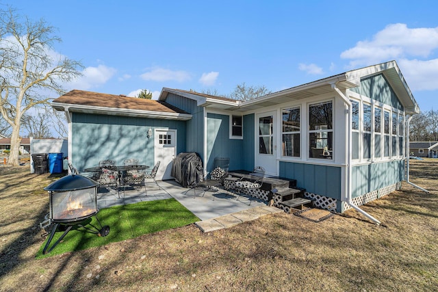 rear view of property with a patio and a fire pit