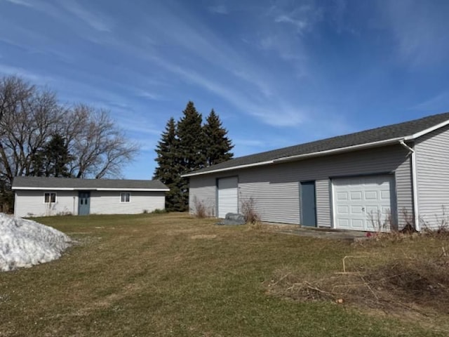 exterior space with a detached garage, a yard, and an outbuilding