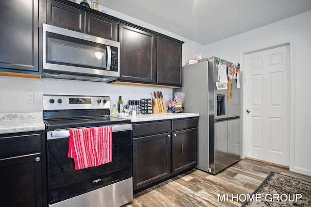 kitchen featuring dark brown cabinetry, stainless steel appliances, light countertops, and light wood-style floors