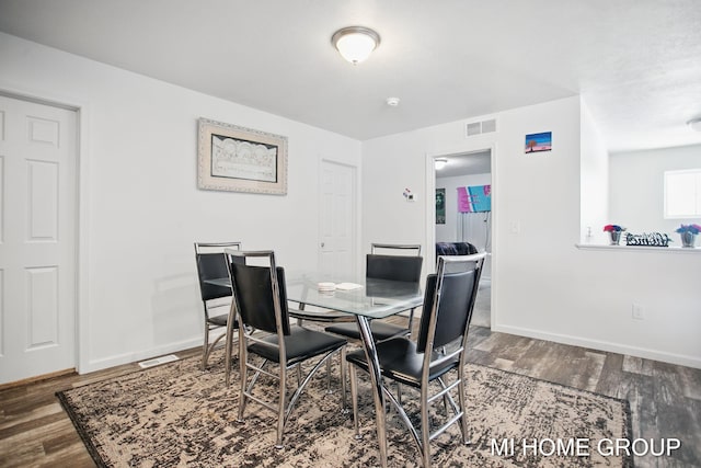 dining space with wood finished floors, visible vents, and baseboards