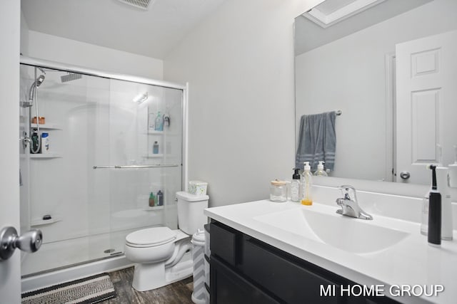 full bathroom with a stall shower, toilet, wood finished floors, and vanity