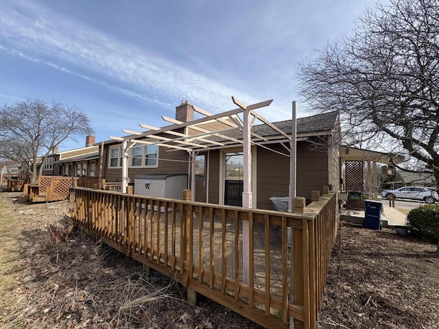 back of property with a chimney, a wooden deck, and roof with shingles