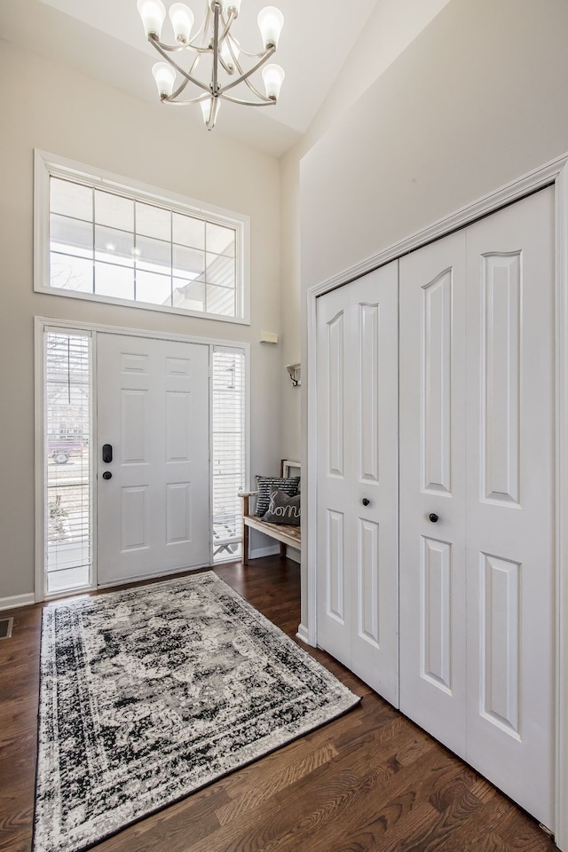 foyer with dark wood-style floors, baseboards, a high ceiling, and an inviting chandelier