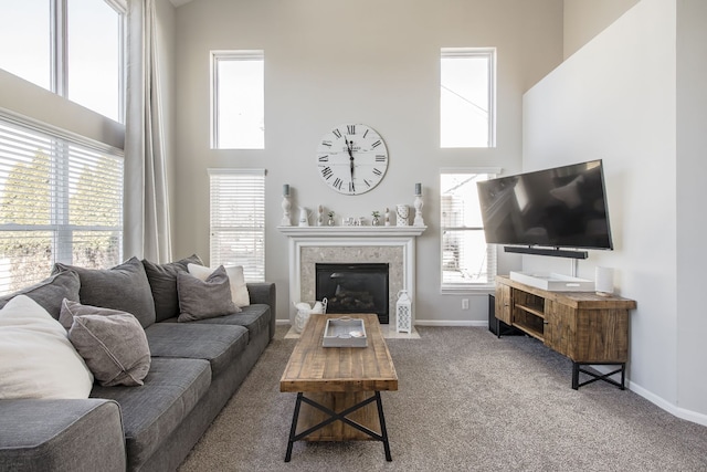 living room featuring carpet flooring, a tile fireplace, a high ceiling, and baseboards