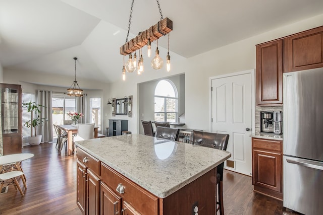 kitchen with a kitchen island, dark wood finished floors, lofted ceiling, plenty of natural light, and freestanding refrigerator