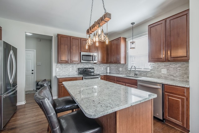 kitchen featuring dark wood-style flooring, appliances with stainless steel finishes, a breakfast bar, and a sink