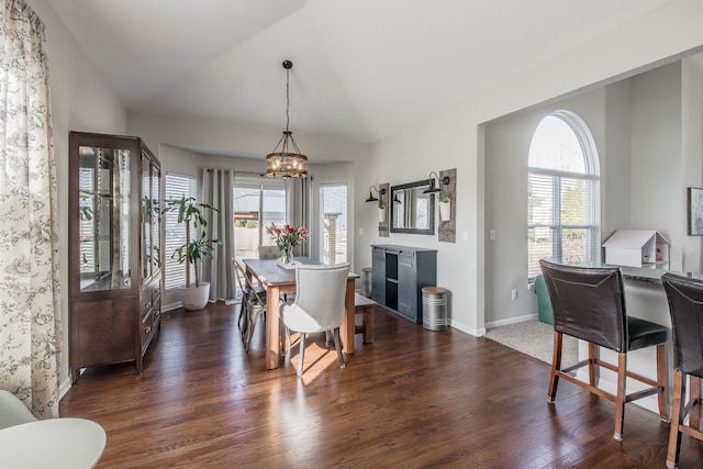 dining space featuring a wealth of natural light, dark wood-type flooring, an inviting chandelier, and vaulted ceiling