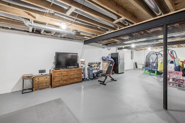 unfinished basement featuring freestanding refrigerator