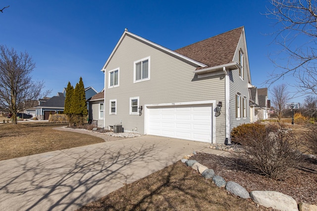 view of side of property featuring an attached garage, driveway, and a shingled roof