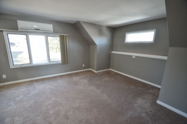 additional living space with an AC wall unit, baseboards, and carpet floors