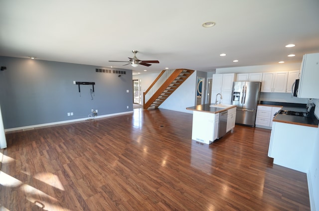 kitchen with a sink, open floor plan, recessed lighting, stainless steel appliances, and dark wood-style flooring