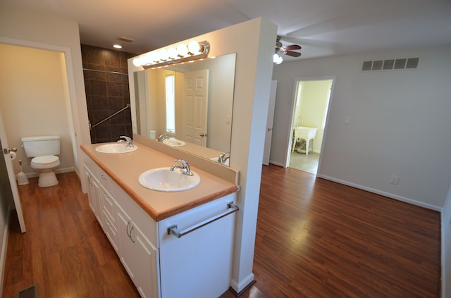 bathroom with a sink, visible vents, toilet, and wood finished floors