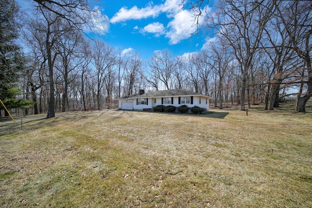 view of front of house with an attached garage, a chimney, and a front yard