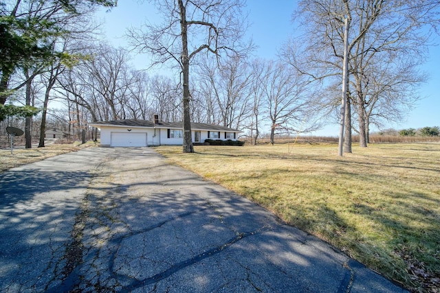 view of front of house with a front yard, an attached garage, driveway, and a chimney