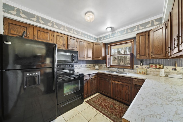 kitchen with a sink, black appliances, light countertops, and light tile patterned floors