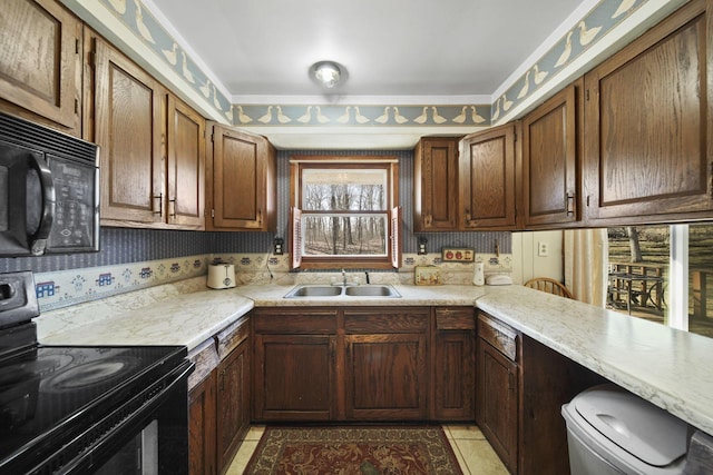 kitchen with a sink, black appliances, light tile patterned floors, and light countertops