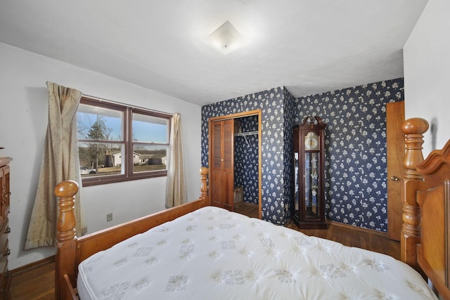 bedroom featuring a closet, wallpapered walls, and wood finished floors