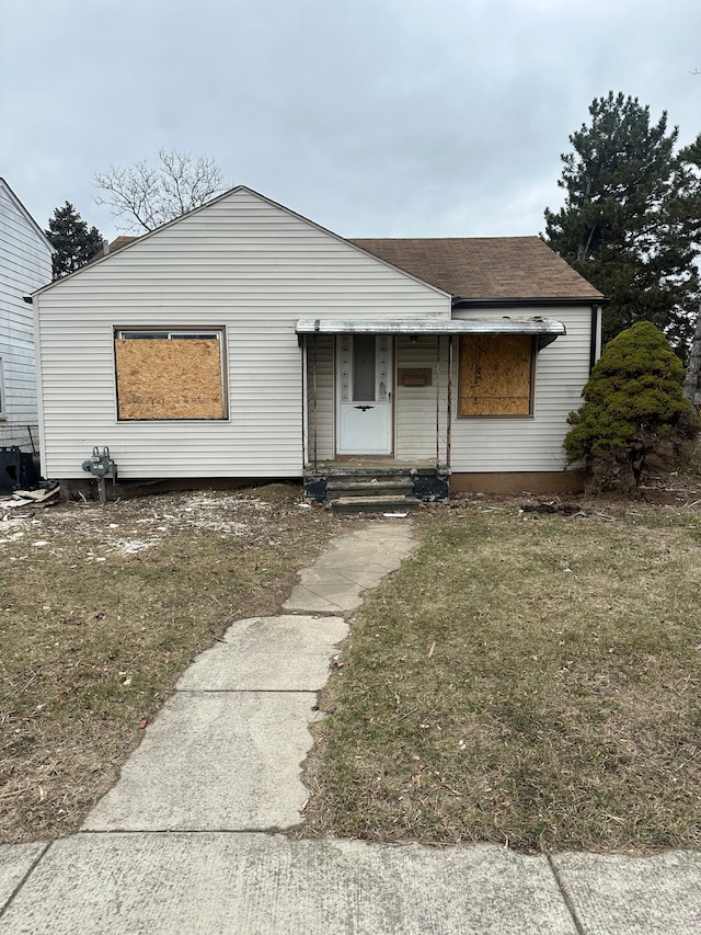 view of front of house with a front yard and roof with shingles