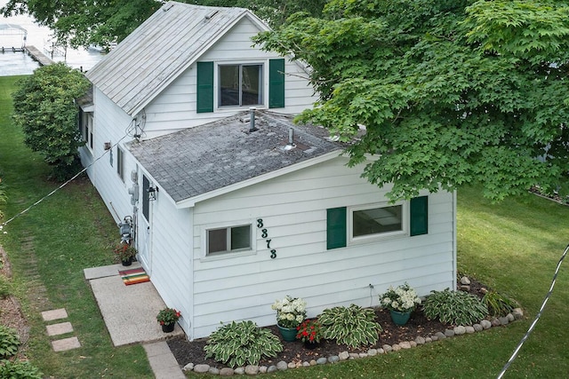 view of side of property with a yard and a shingled roof