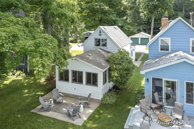 rear view of house with an outdoor fire pit, a wooden deck, a yard, and roof with shingles