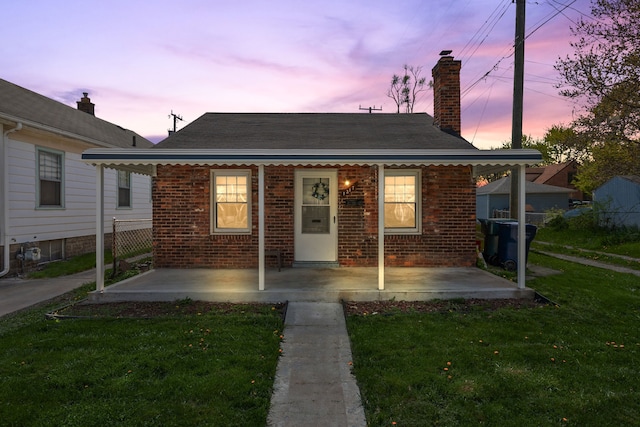 bungalow-style home featuring a front lawn, covered porch, brick siding, and a chimney