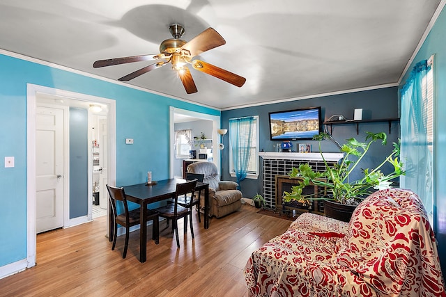 dining area with baseboards, wood finished floors, crown molding, and a tiled fireplace