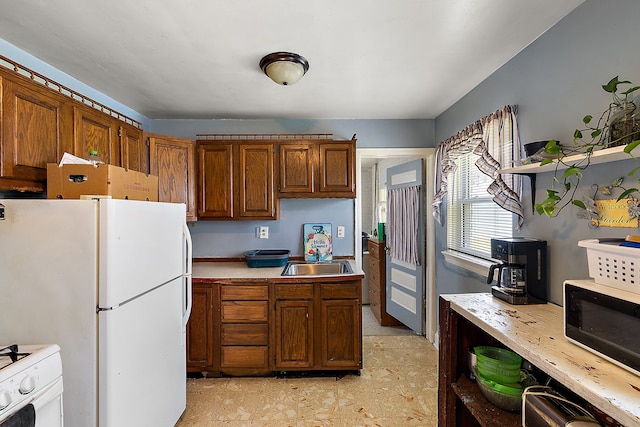 kitchen with a sink, light countertops, brown cabinets, white appliances, and open shelves